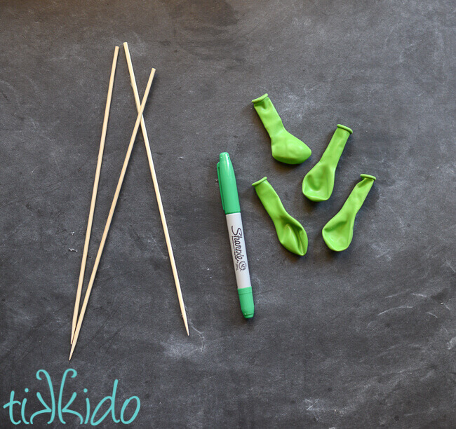 Materials for making watermelon balloons on a chalkboard background.