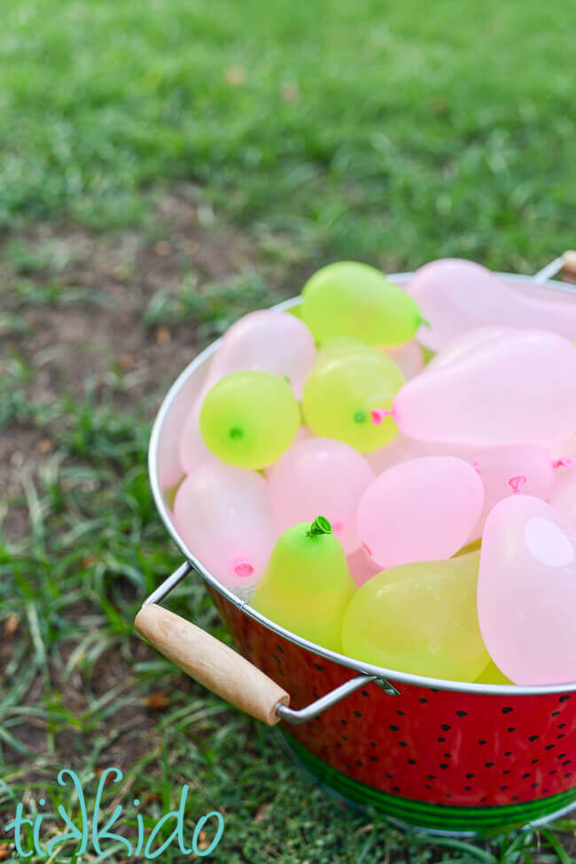 Galvanized tub painted like a watermelon filled with pink and green water balloons at the Watermelon themed party.