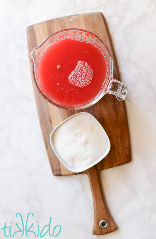 Watermelon syrup ingredients in bowls on a wooden cutting board.