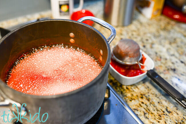 Watermelon syrup being boiled in a pot on the stove.