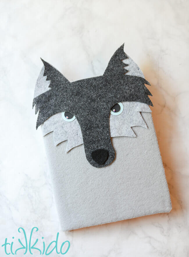 Felt wolf notebook on a white marble background.