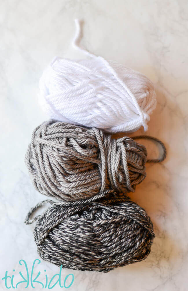 white, grey, and dark grey yarn on a white marble background.