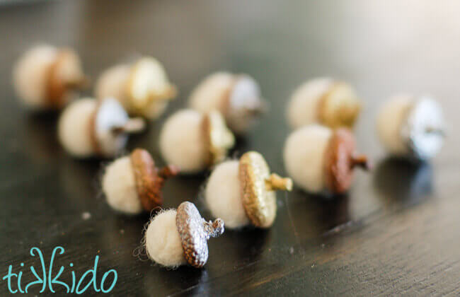 Felt acorns with real acorn caps on a wooden table.