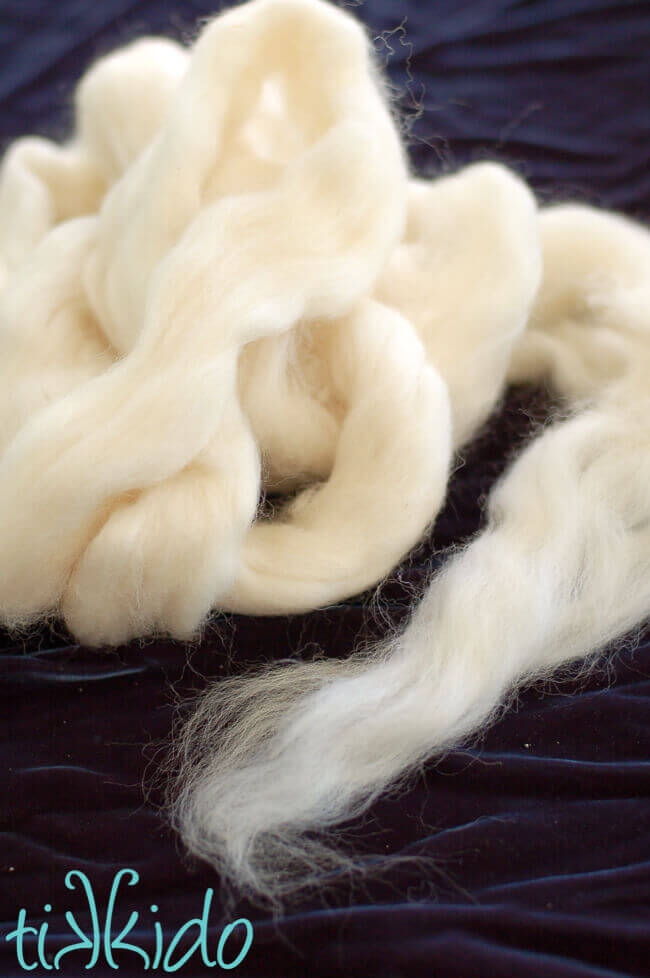 White wool roving piled on a dark blue velvet background.