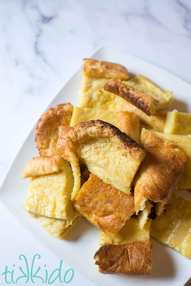 Pieces of Yorkshire pudding on a white plate on a white marble background.