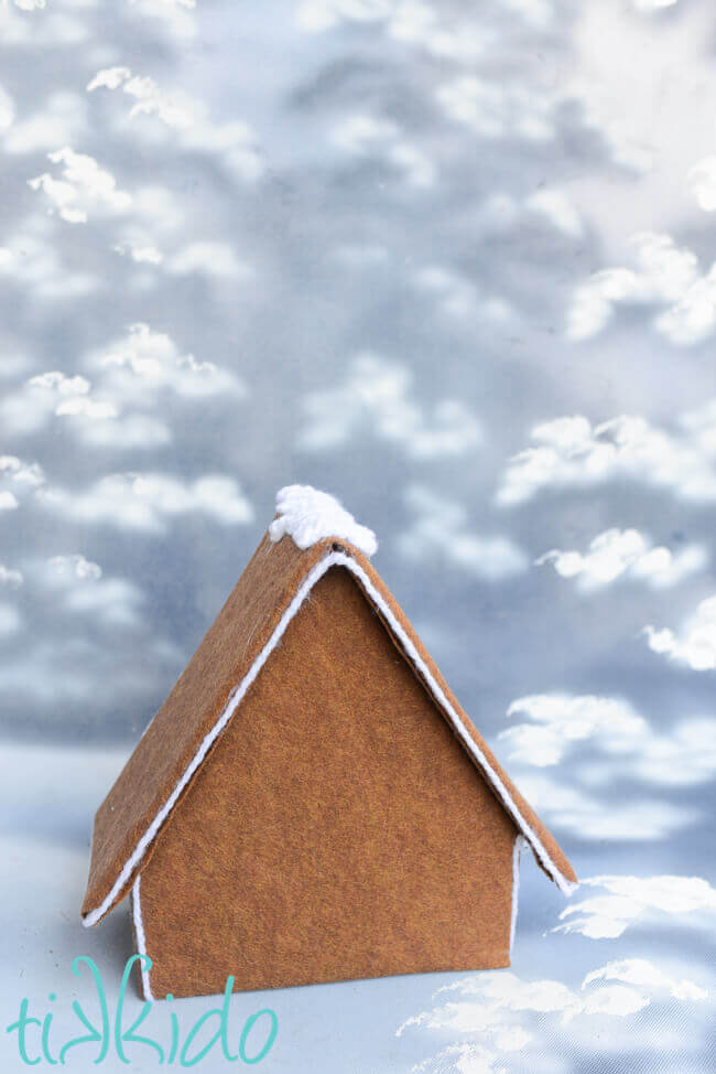 Felt Gingerbread House, undecorated, on a snowy photography backdrop.