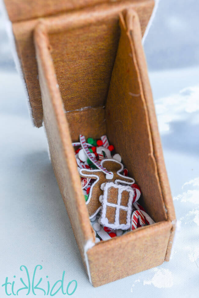 Felt gingerbread house with the roof flap open, revealing storage for the items used to decorate the felt gingerbread house.