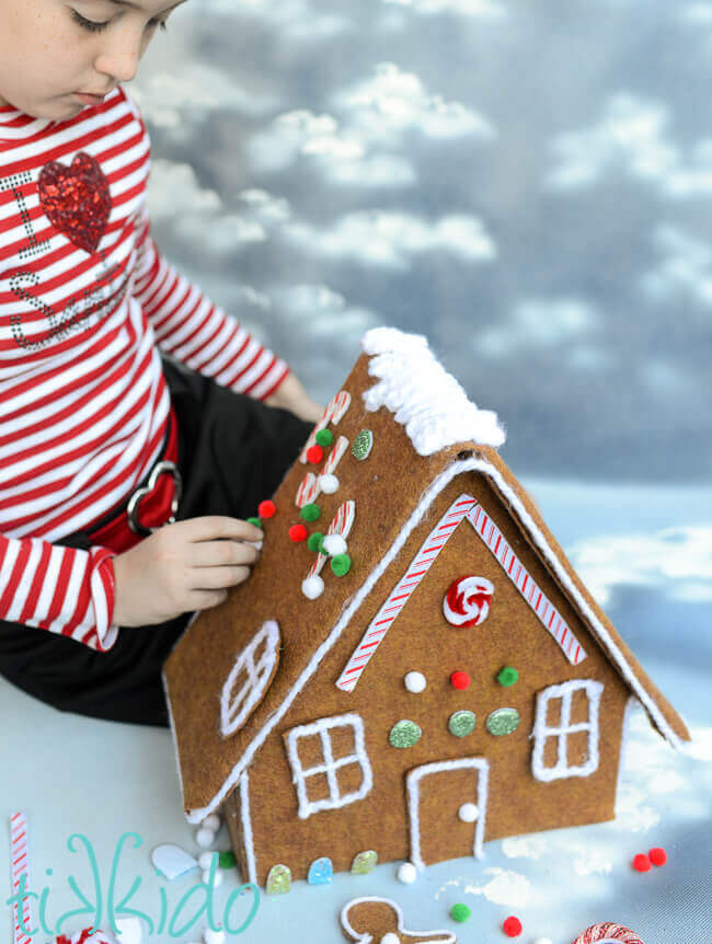 Little girl decorating a Felt Gingerbread House.