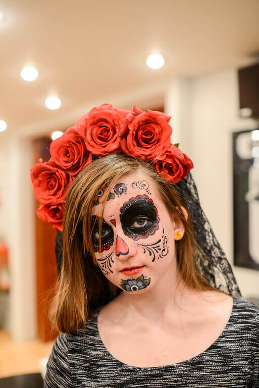 Girl wearing a red rose and black lace day of the dead headpiece.
