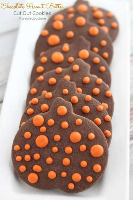 Chocolate peanut butter cut out sugar cookies decorated as polka dot pumpkins.