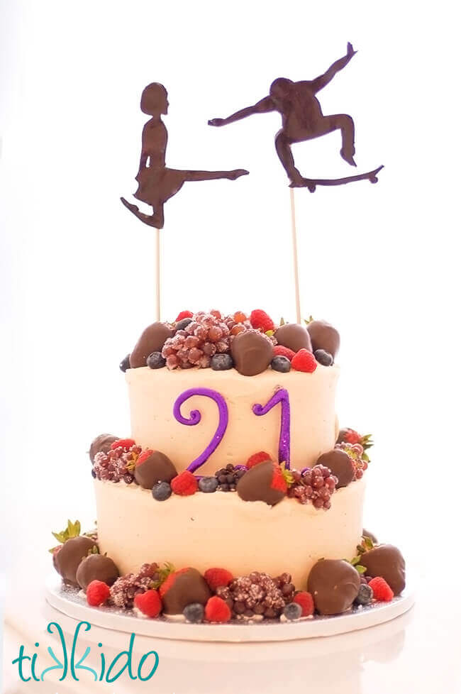 21st birthday cake iced with Bailey's frosting and topped with chocolate covered fruits and an Irish dancer and a skateboarder cake topper.