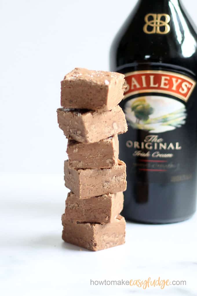 Stack of Baileys Fudge in front of a bottle of Baileys Irish Cream.