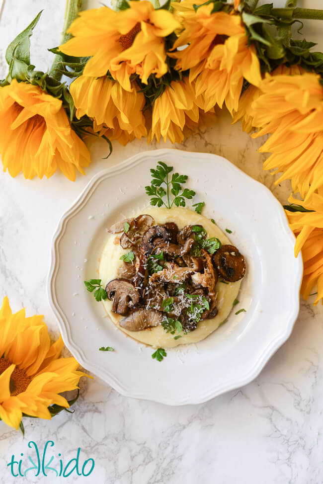 Cheesy polenta recipe topped with oven roasted mushrooms on a white plate.
