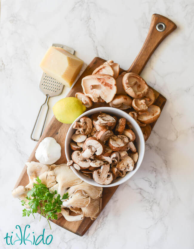 Ingredients for oven roasted mushrooms on a wooden cutting board.