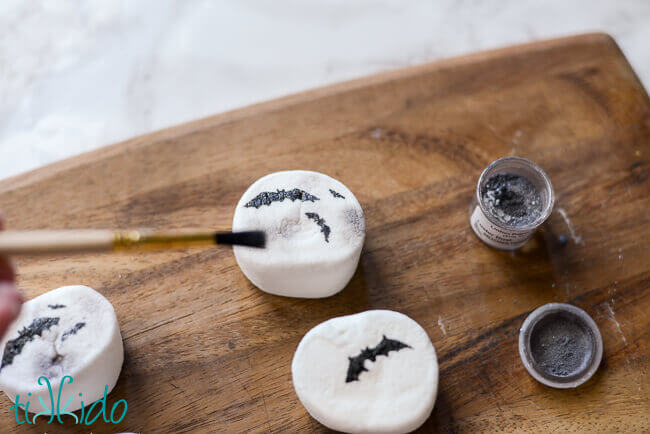 Round marshmallows being decorated to look like full moons with bats flying across in silhouette.