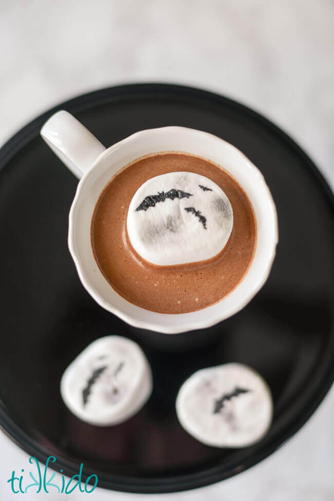 Hot cocoa with a marshmallow decorated to look like a full moon for Halloween.