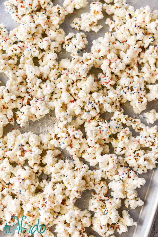 Birthday cake popcorn with sprinkles on a baking sheet.
