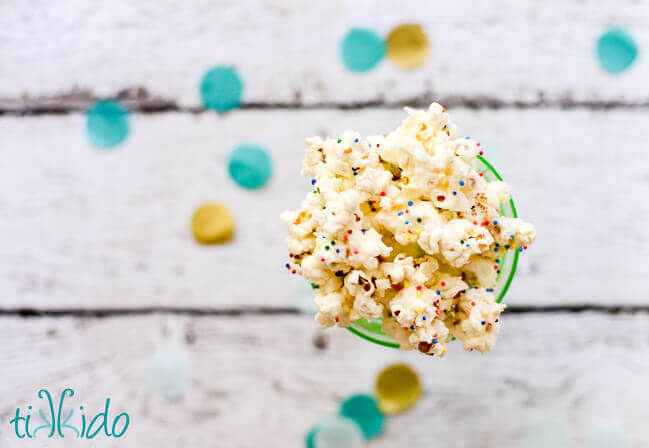 Birthday cake popcorn with sprinkles in a green glass dish.