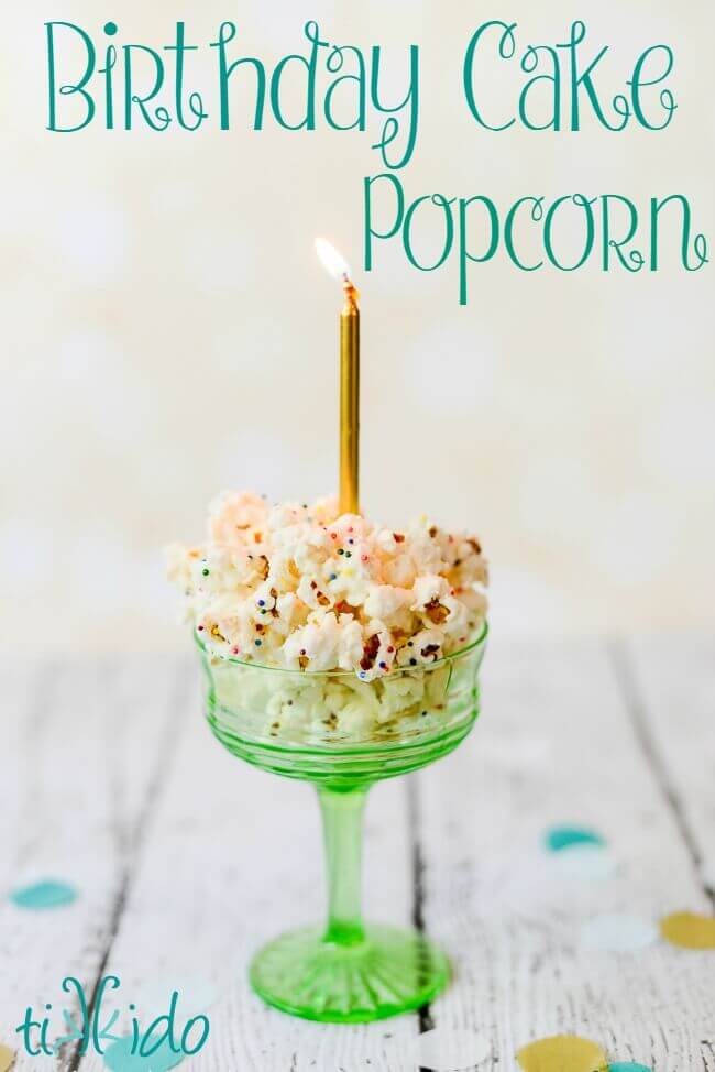 Birthday cake popcorn in a green glass dish, topped with a gold birthday candle.