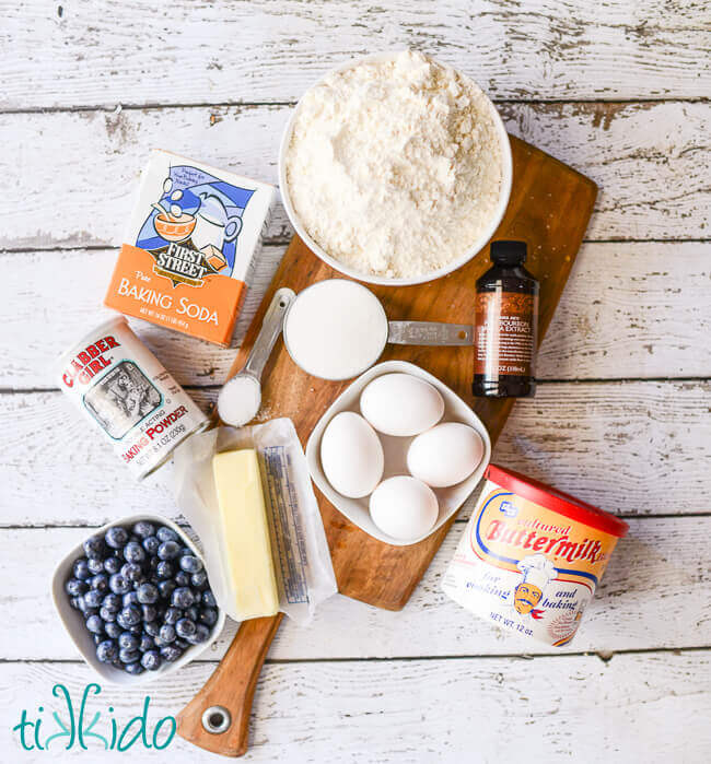 Buttermilk pancake ingredients on a wooden cutting board on a white weathered wood table.