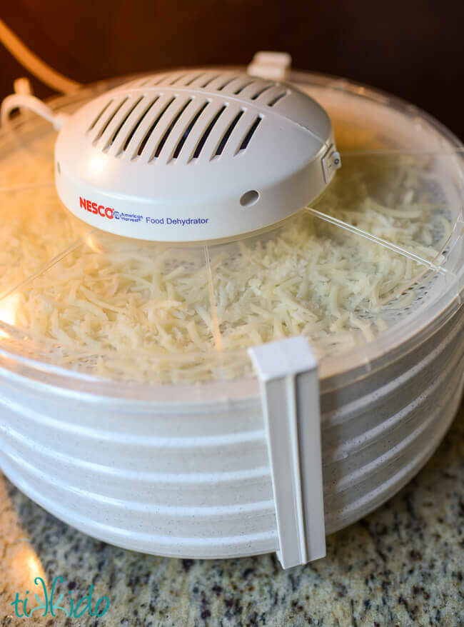 Dehydrator filled with trays of shredded cheese.