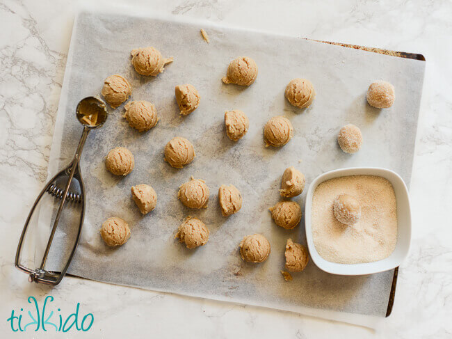 Browned butter cookie dough scooped and being rolled in sugar.