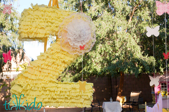 Store bought piñata shaped like a number 2 covered in light yellow ruffled crepe paper.