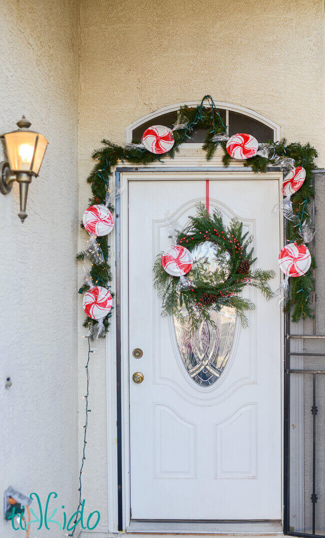 Easy, inexpensive, large scale peppermint decorations for Christmas made from paper plates decorating a wreath and garland.