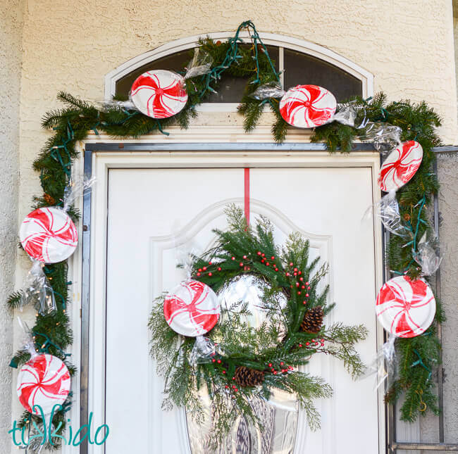 Easy, inexpensive, large scale peppermint decorations for Christmas made from paper plates decorating a wreath and garland.