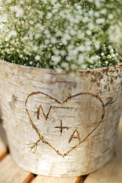 Birch bark covered zinc floral container with the letters N + A in a heart carved into the bark.