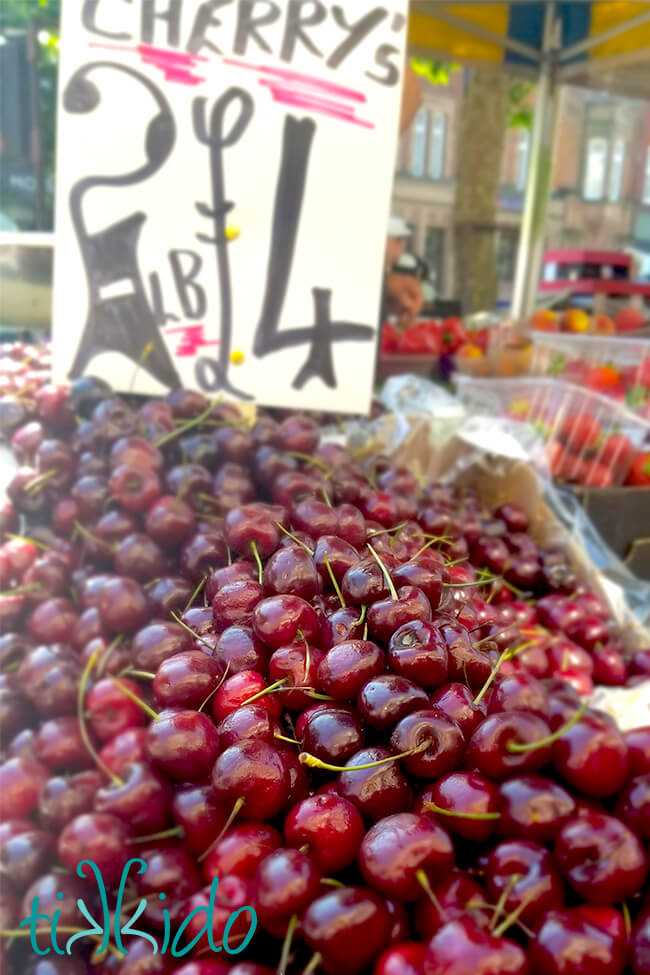 Large pile of fresh cherries for sale at a farmer's market.