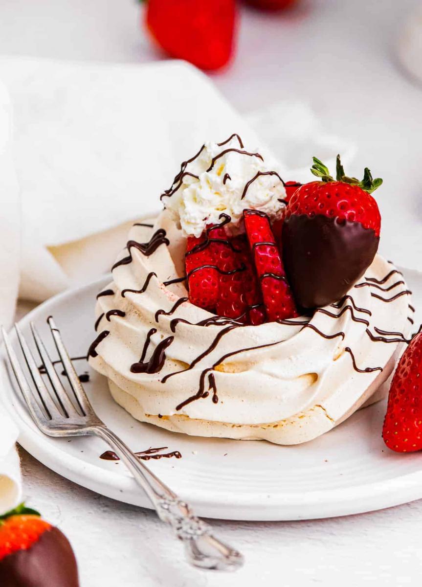 Chocolate covered strawberry pavlova on a white plate.