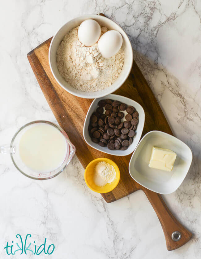 Ingredients for chocolate waffles recipe set out on a wooden cutting board.