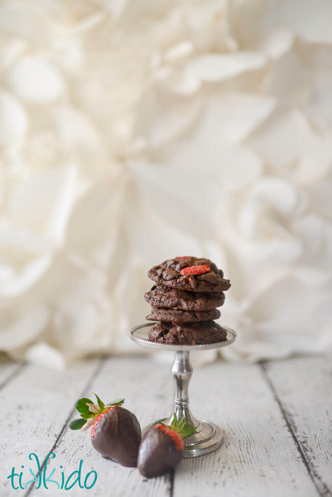 Stack of Chocolate Covered Strawberry Cookies on a small silver stand, with two fresh chocolate covered strawberries sitting at the base of the stand.