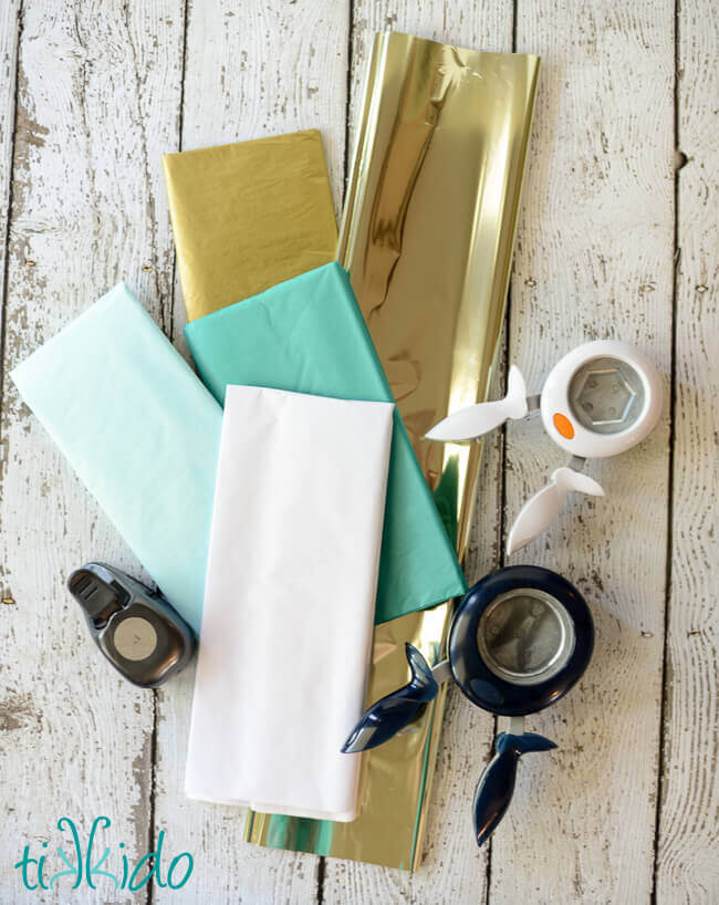 Tissue paper and paper punches on a weathered white wood background.