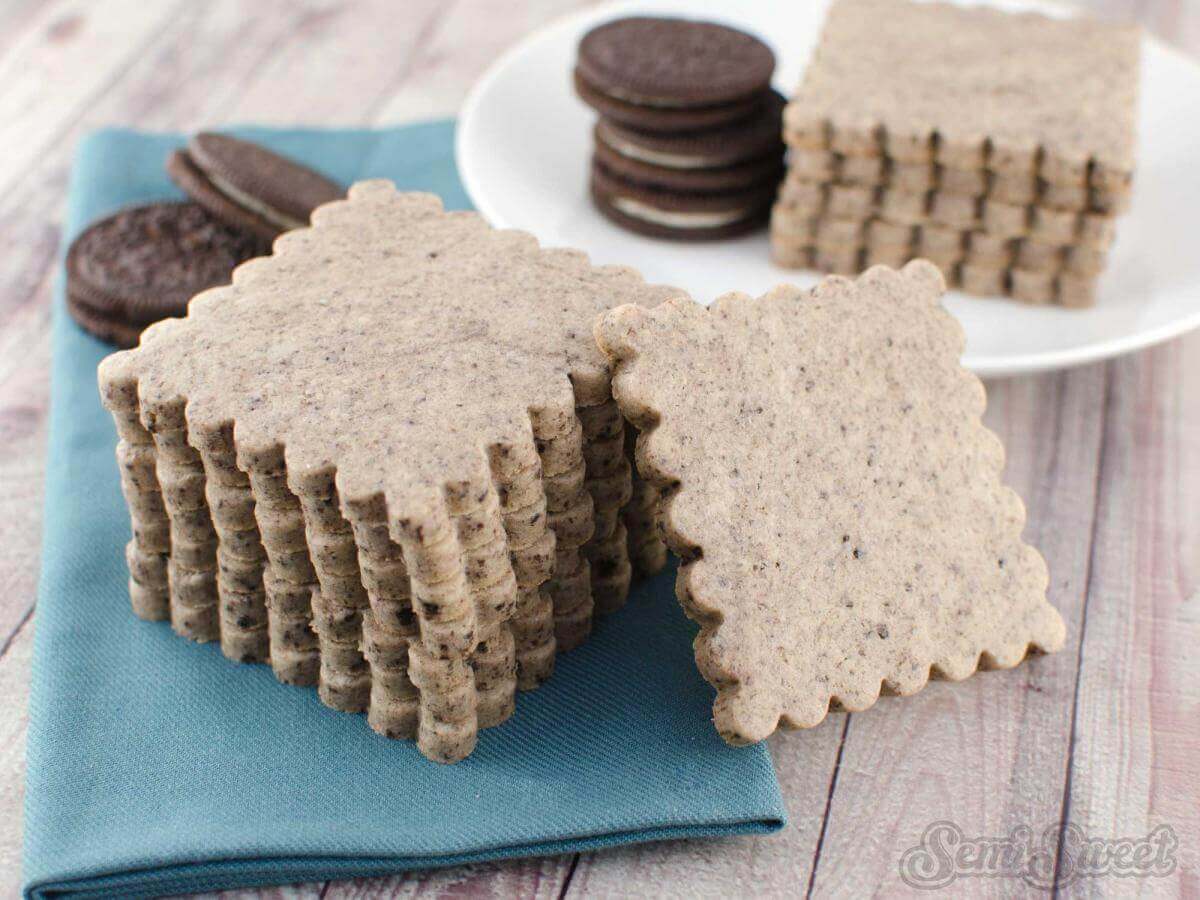 Cookies and cream cut out sugar cookies on a blue napkin on a wooden surface.