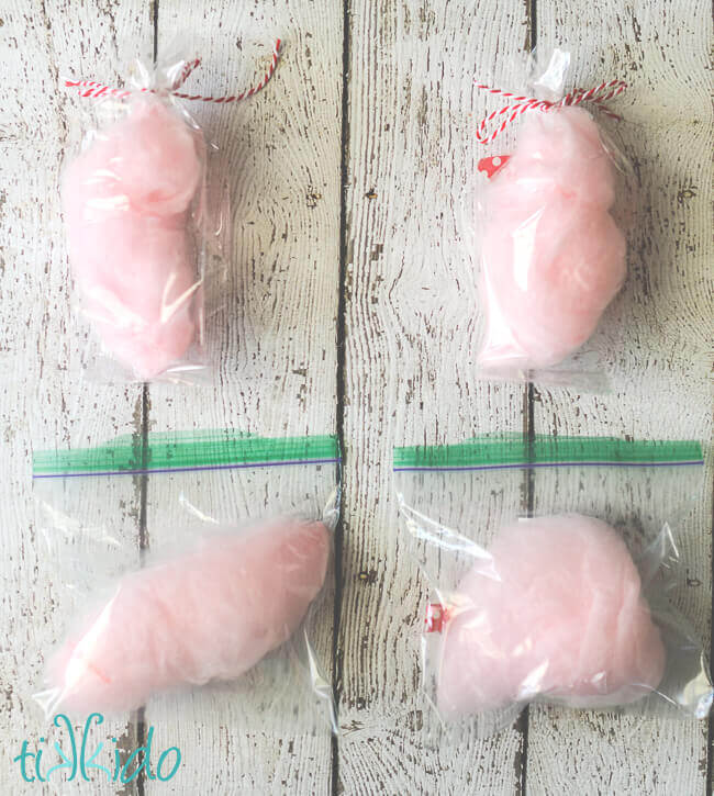 Four bags of pink cotton candy on a white weathered wood backdrop.  Two bags tied with baker's twine, the other two are ziplock bags.
