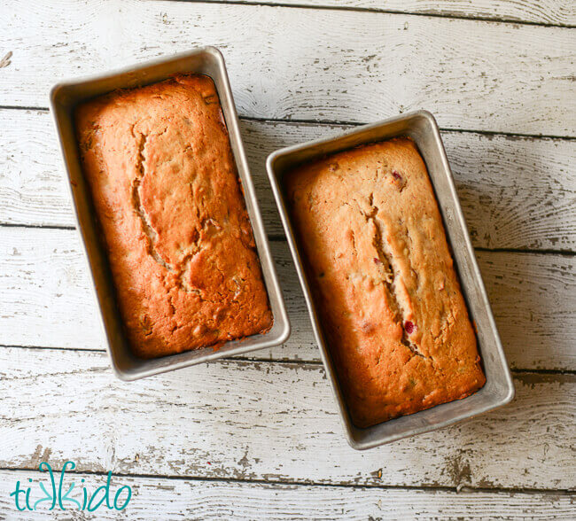 Two loaves of baked Cranberry Nut Bread on a white weathered wood background.