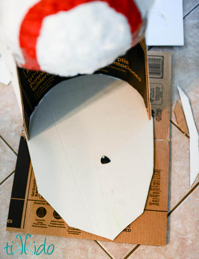 Store bought baseball pinata being taped and glued to cardboard to form a Dalek Piñata