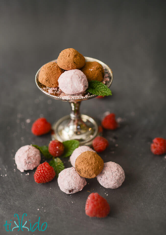 raspberry dark chocolate truffles dusted in raspberry powdered sugar and cocoa powder, on a black chalkboard background.