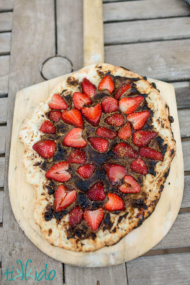 Dessert pizza with Nutella and strawberries on a wooden pizza peel
