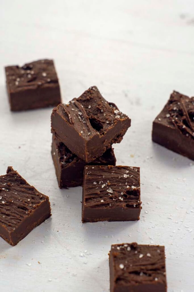Pieces of double chocolate fudge sprinkled with sea salt on parchment paper.