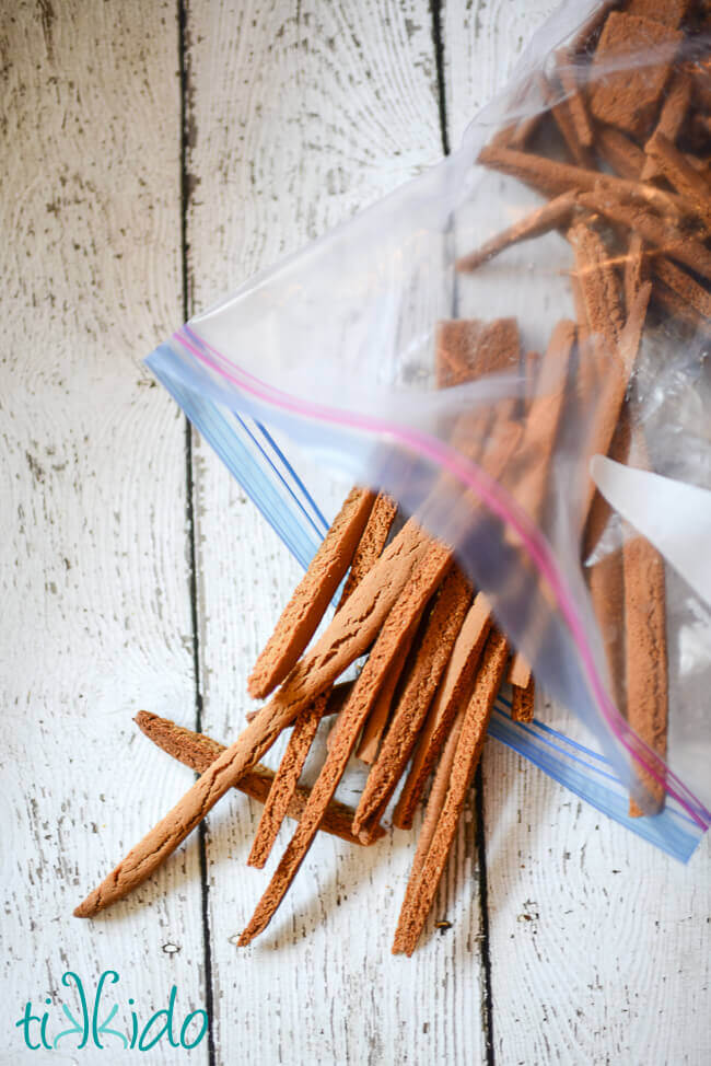 Gingerbread scraps and trimmed pieces in a ziplock bag on a white wooden surface.