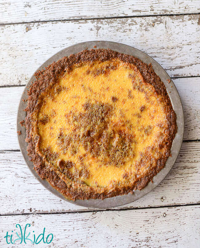 Eggnog custard pie baked and cooling on a white wooden table.