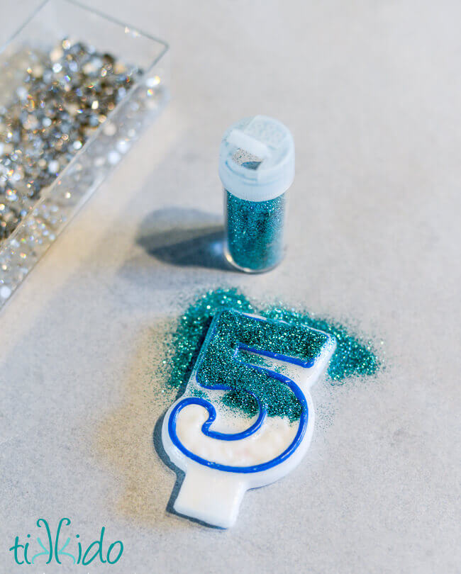 Covering the plain number 5 birthday candle with glitter.