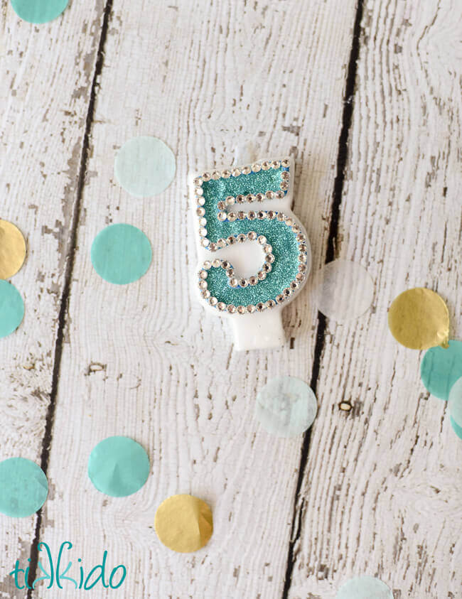 Number five birthday candle embellished with glitter and rhinestones to match a party theme.