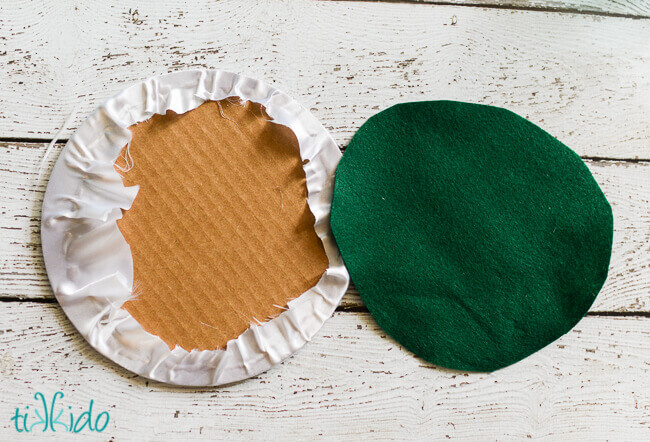 Cardboard cake round being covered with satin and felt to make a disc shaped fascinator.