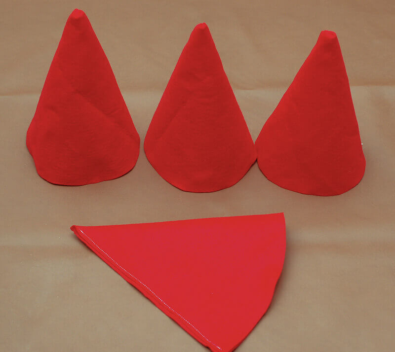 Three gnome hats sitting beside a gnome hat turned inside out and sewn up the back.