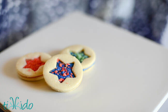 Three patriotic sandwich sugar cookies filled with red and blue buttercream and pop rocks candies.