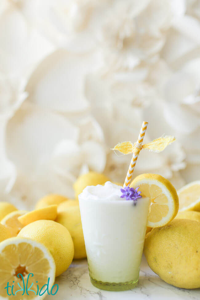Frozen Lemonade with a yellow straw surrounded by fresh lemons.